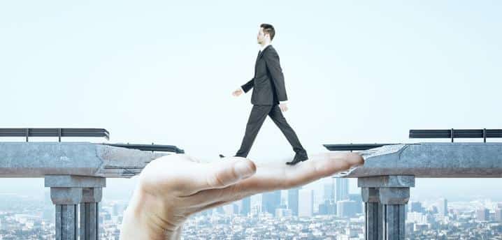 Man walking across gap with help with help of someone's hand