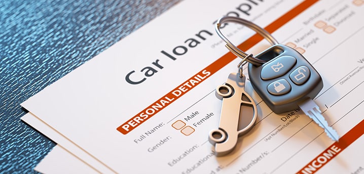 car key with a small car keychain sitting on a car loan application form