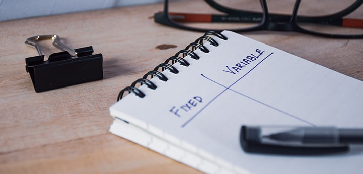 Fixed and variable written on a pad of paper