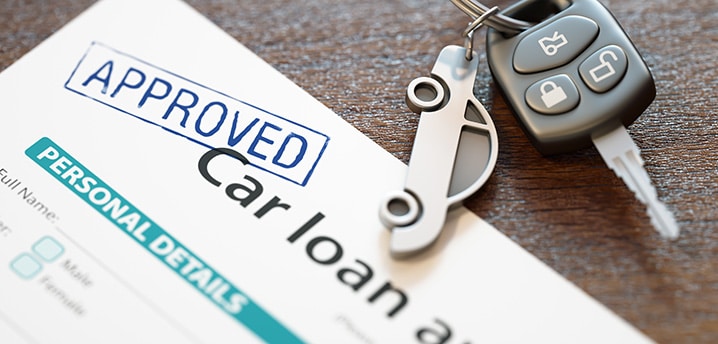 Set of car keys sitting on top of an approved auto loan application