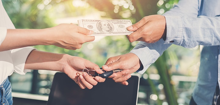 Two people exchanging money for car keys