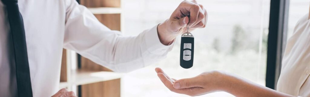 bank employee handing car keys to new car buyer