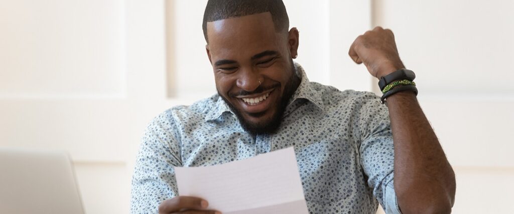 Man happy and excited while reading a piece of paper