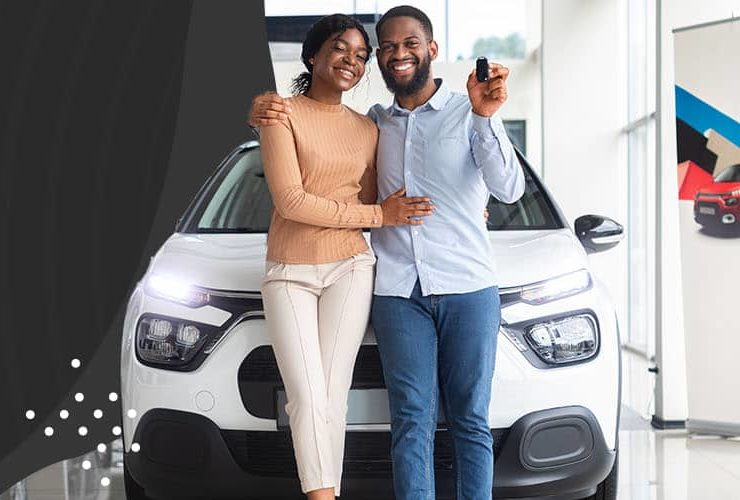 Couple standing together in front of a car smiling and holding the keys