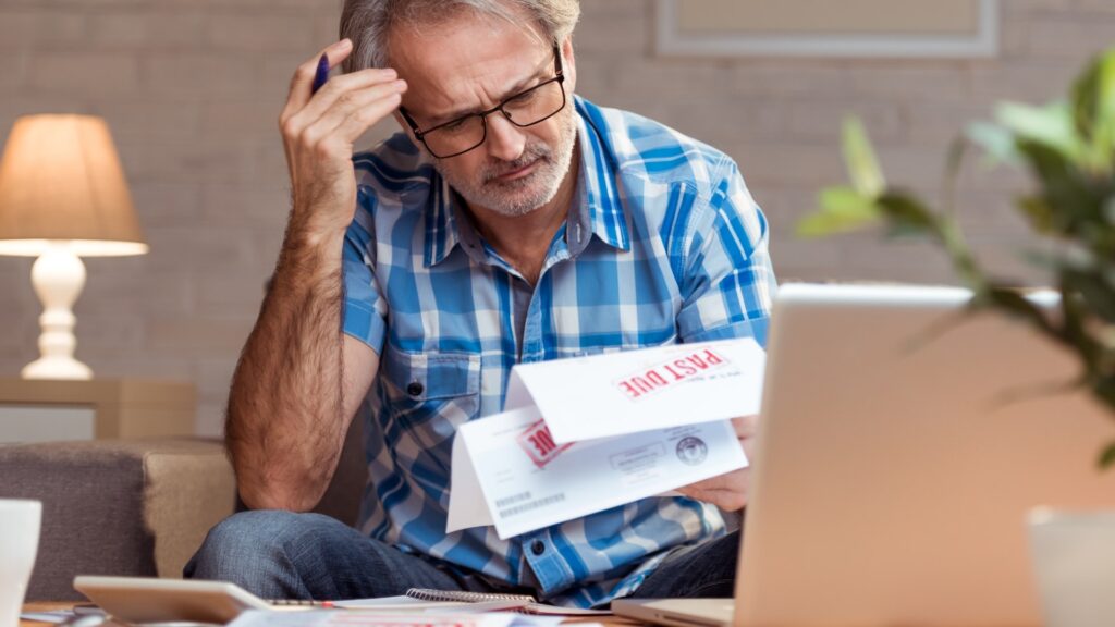 Man looking down at bills marked past due