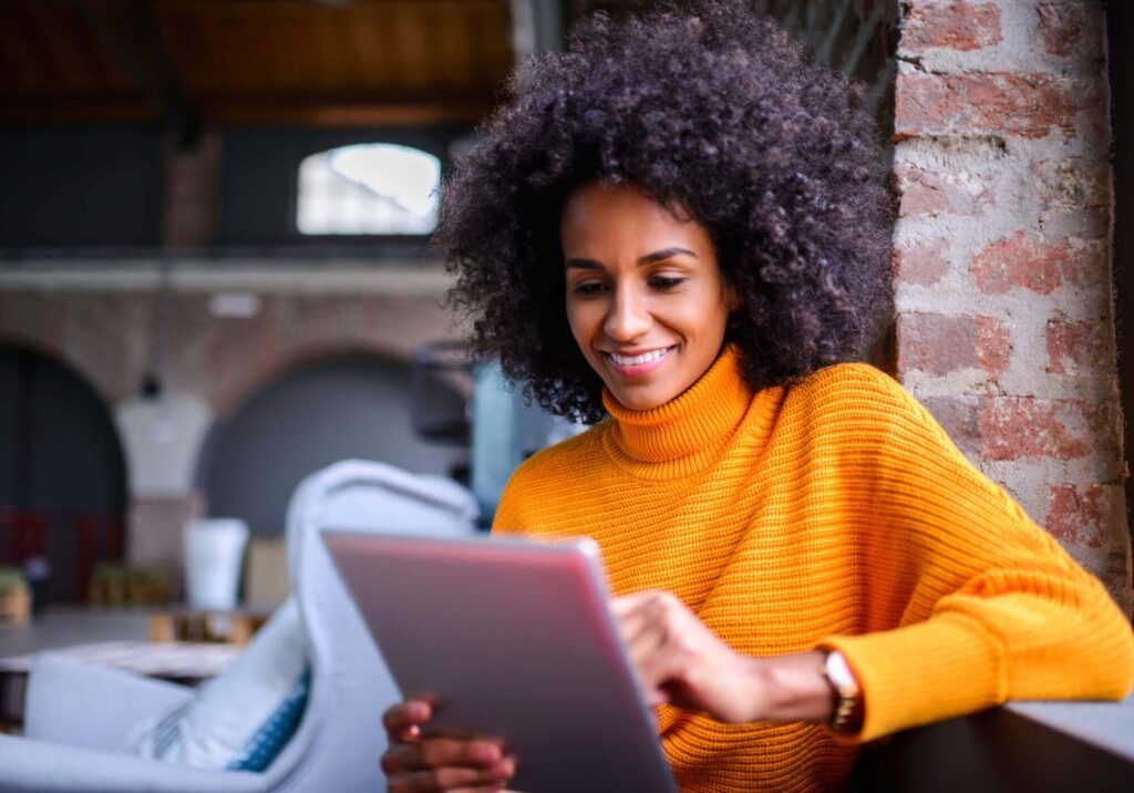 Image of woman checking for current auto refinance rates online using a tablet.