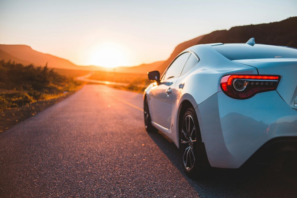 White car driving on road during a sunset.