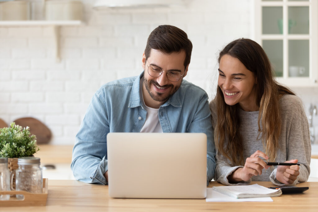 Young man and women smiling working on a computer together.