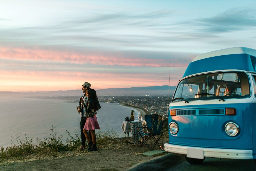 People looking at sunset next to van.