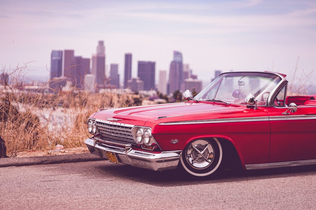 Old school red car with city in the background of image.