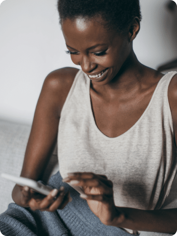 Woman browsing for auto loan rates on her phone, comfortable at home.