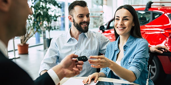 Smiling, happy couple accepting keys to their new car