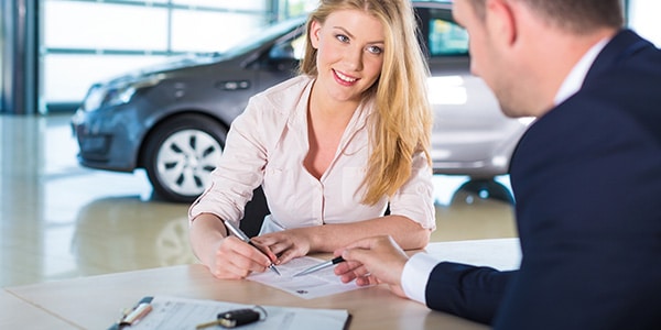 woman signing a document for a new car