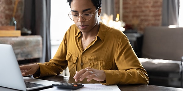 woman using a calculator and her laptop