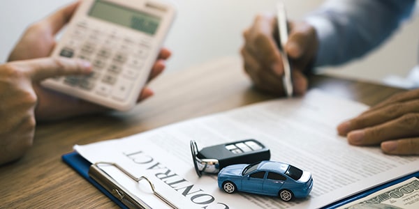 signing a contract with key fob and toy car sitting on top