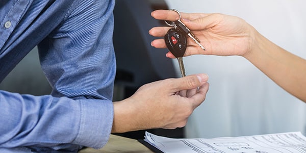 person handing car keys to another individual