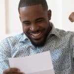 Man happy and excited while reading a piece of paper
