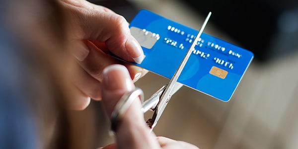 person using scissors to cut a credit card in half