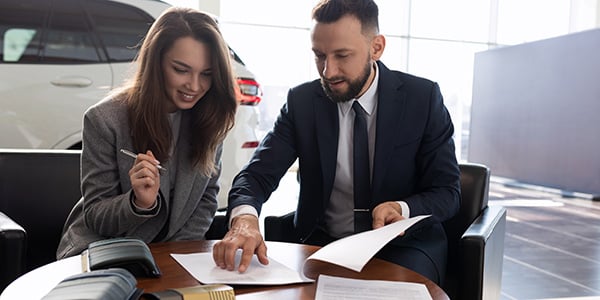 woman signing for a new car at a dealership