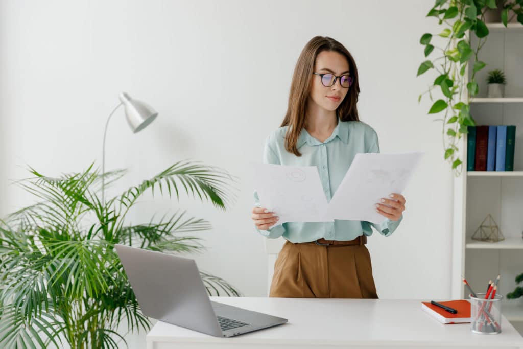 Woman standing at a table looking through paperwork